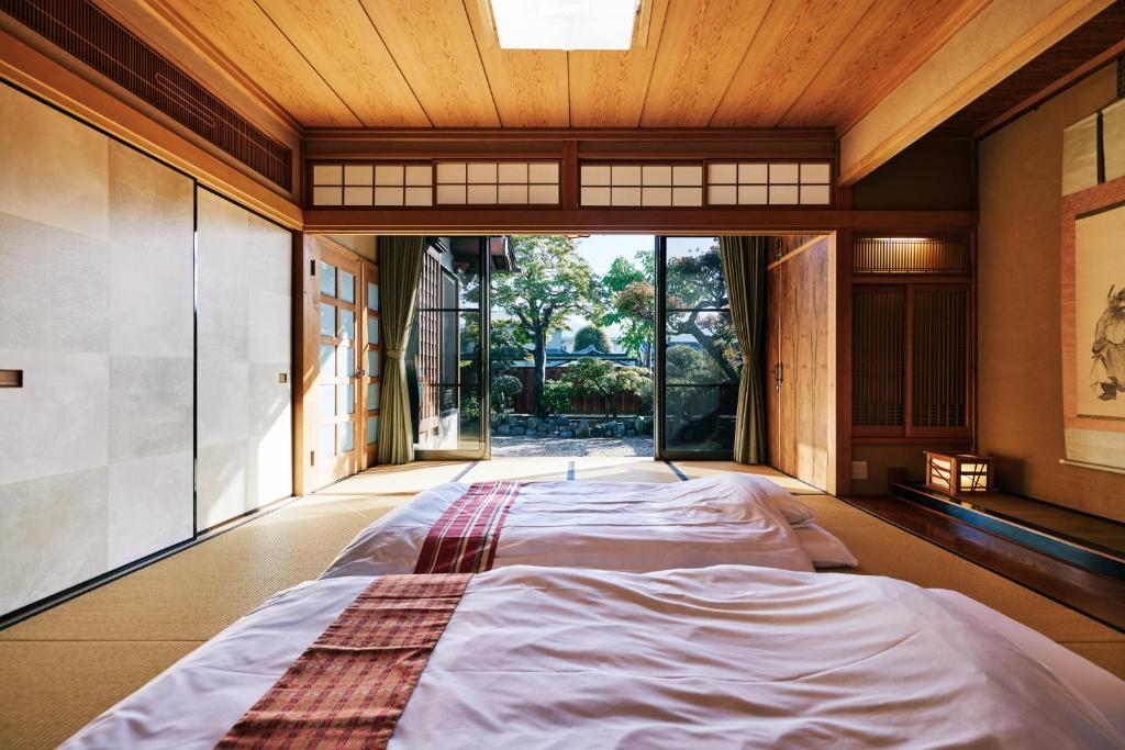 un grand lit dans une chambre avec une grande fenêtre dans l'établissement 町住客室 秩父宿, à Chichibu