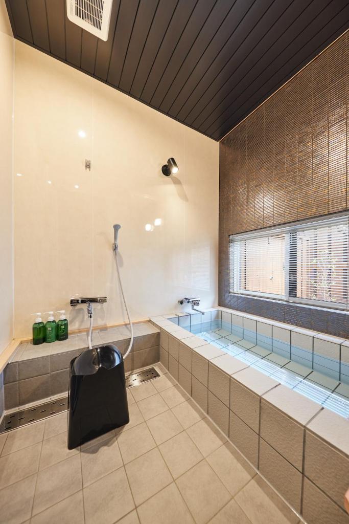 une grande salle de bains avec une piscine et une fenêtre dans l'établissement 町住客室 秩父宿, à Chichibu