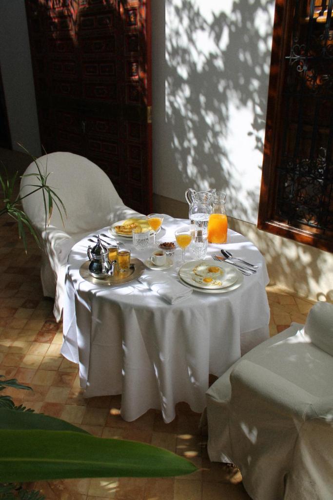 une table blanche avec des plaques de nourriture et des oranges dans l'établissement Riad El Morocco Hotel, à Marrakech