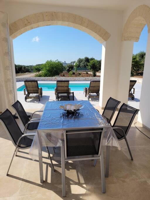 - une table à manger avec des chaises et une vue sur la piscine dans l'établissement Villa Dolce Far Niente Ostuni, à Ostuni