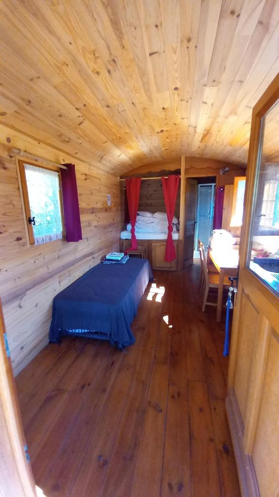 - une chambre dans une cabane en rondins avec un lit dans l'établissement Les ROULOTTINS, à Briançonnet