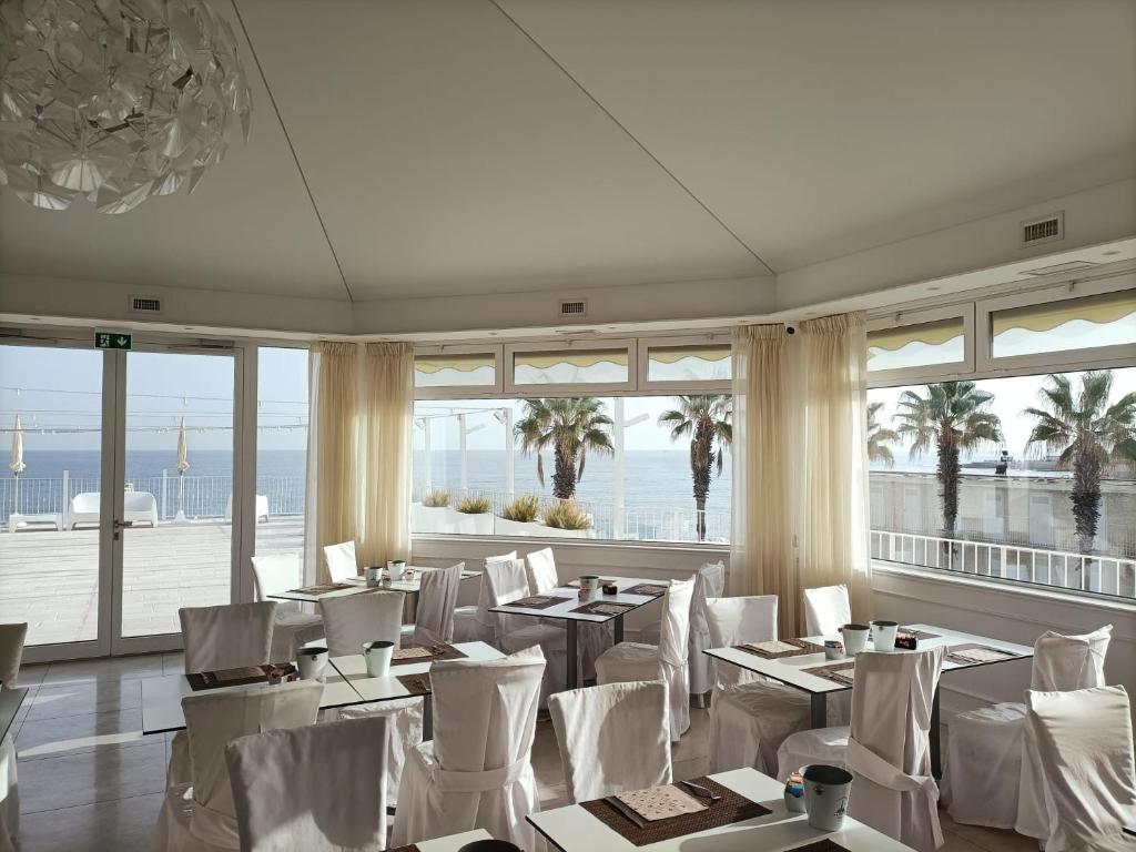 un restaurant avec des chaises et des tables blanches et des fenêtres dans l'établissement Hotel Lafayette, à Giovinazzo