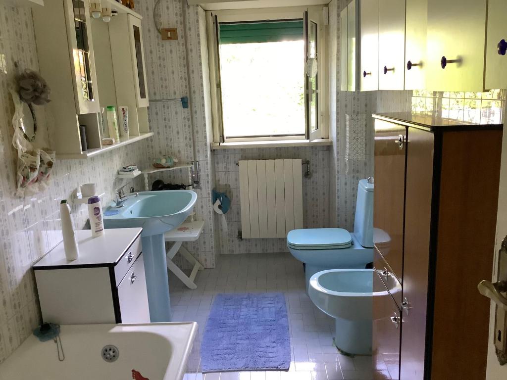 La salle de bains est pourvue de toilettes bleues et de 2 lavabos. dans l'établissement Villa Nanda a 15 minuti da Roma piscina esclusiva , villa nella natura, à Formello