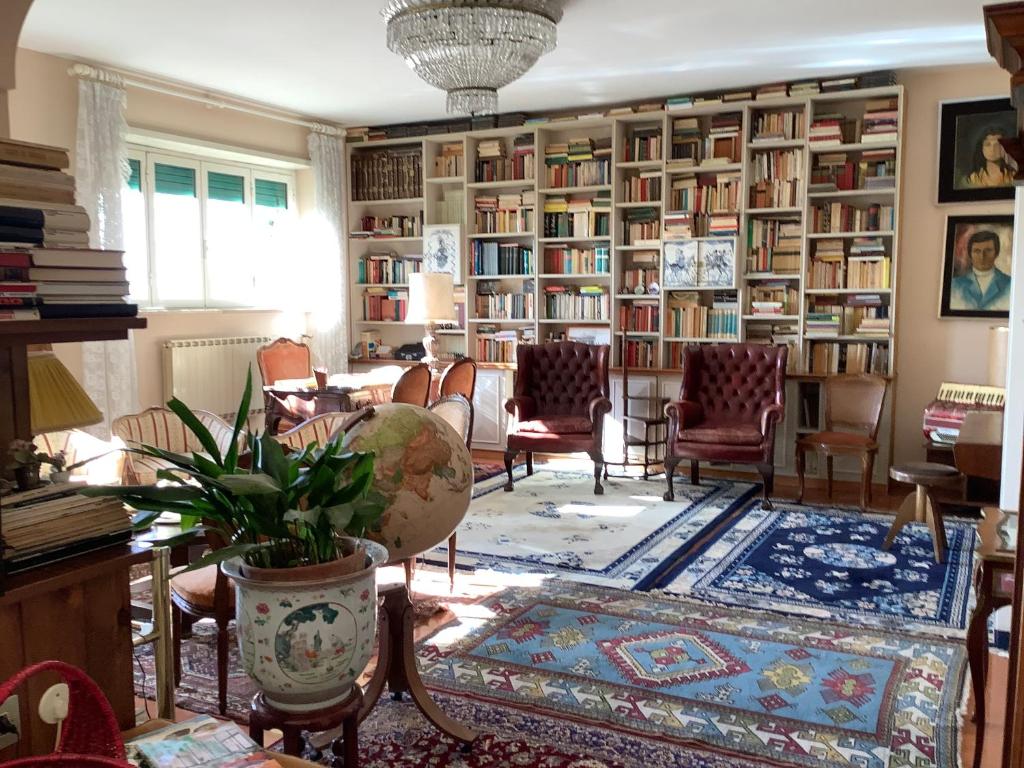 une bibliothèque avec des chaises et des étagères dans l'établissement Villa Nanda a 15 minuti da Roma piscina esclusiva , villa nella natura, à Formello