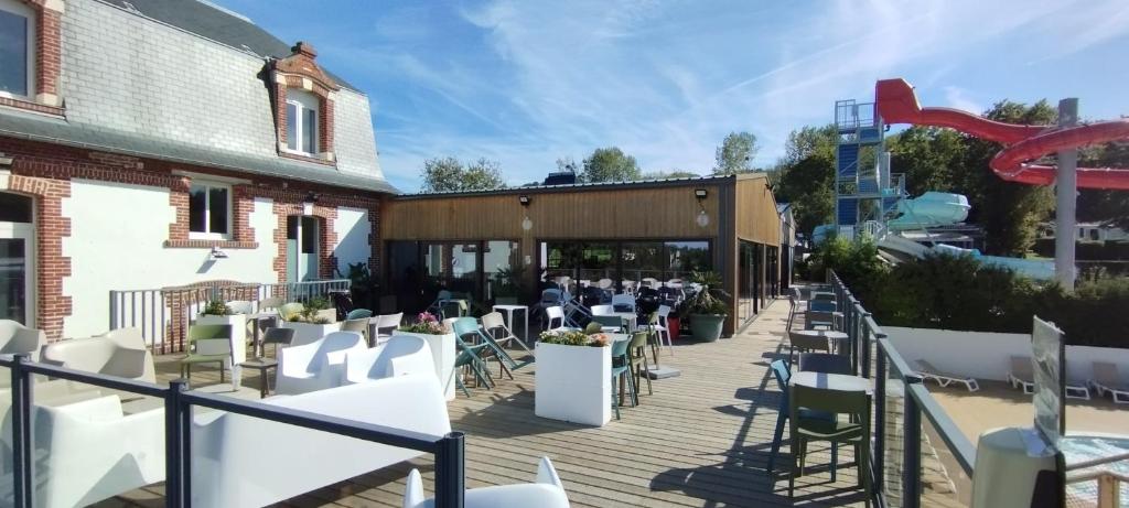 une terrasse avec des tables et des chaises et un bâtiment dans l'établissement LJ Cosy Lodge - Mobilhome, à Houlgate