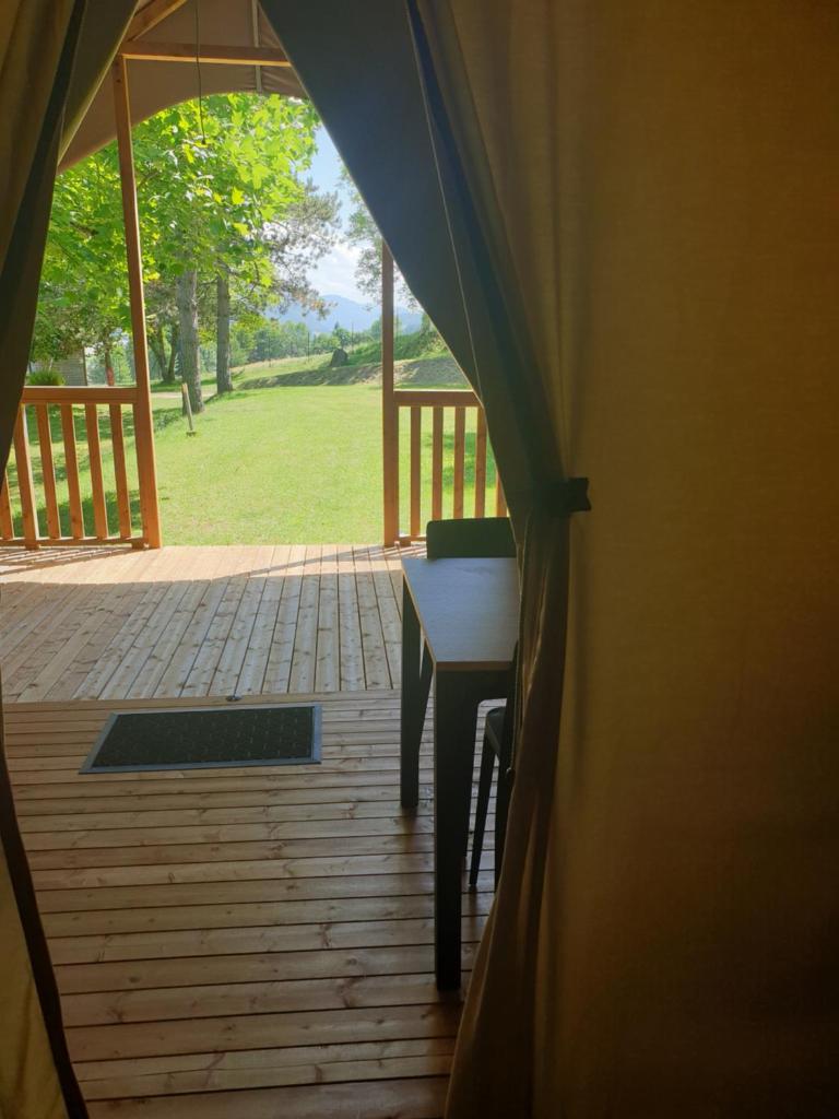 une tente avec une table et une vue sur la cour dans l'établissement lodge du camping la Porte St Martin, à Saint-Martin-en-Vercors