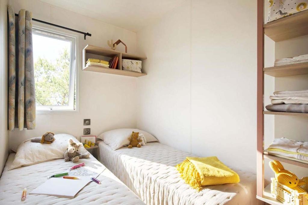 deux lits jumeaux dans une chambre avec fenêtre dans l'établissement Camping Le Ragis, à Challans 37 autres photos