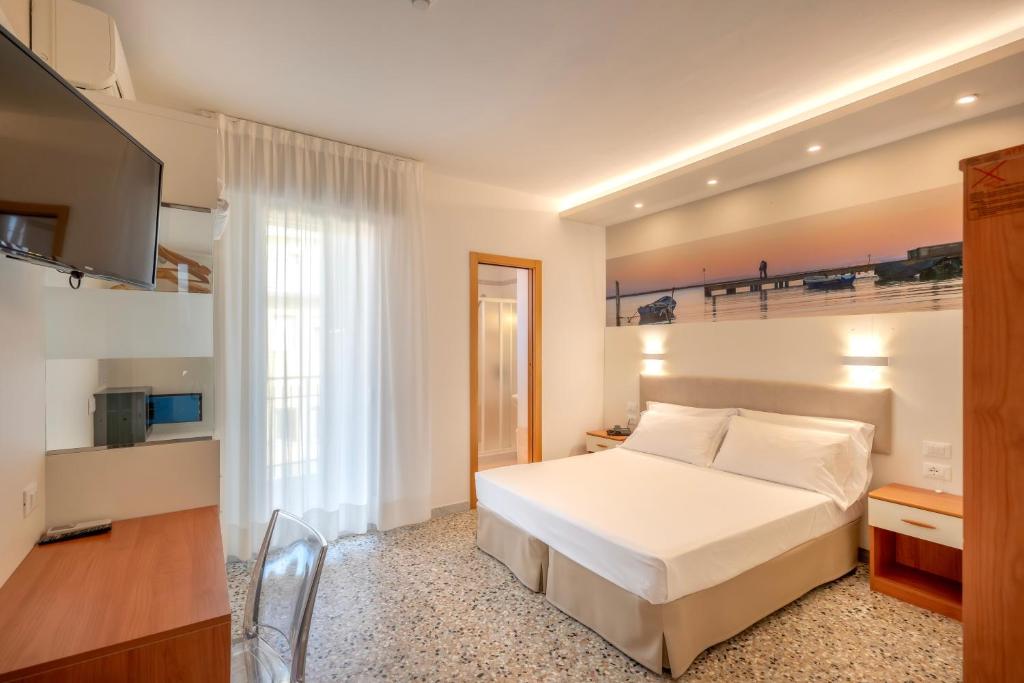 une chambre avec un lit blanc et une télévision dans l'établissement Hotel Atenea Golden Star, à Caorle