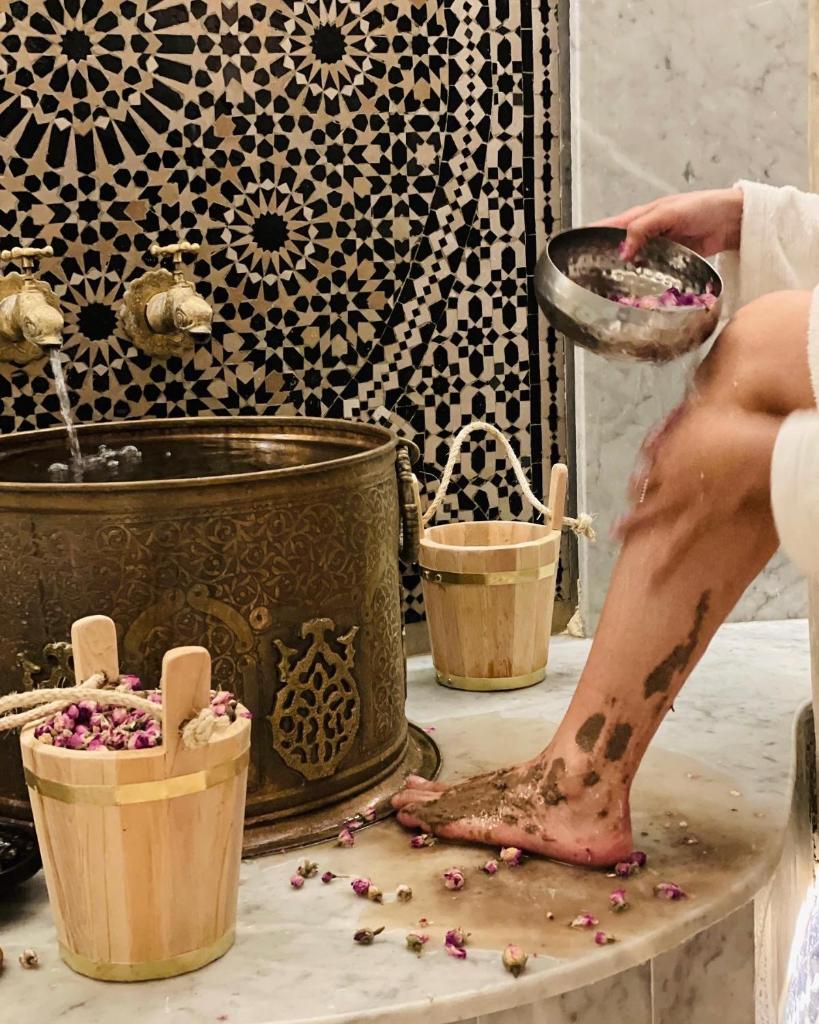 une femme dans une salle de bains avec son pied sur une planche de découpe dans l'établissement Riad Pacha Palace, à Fès