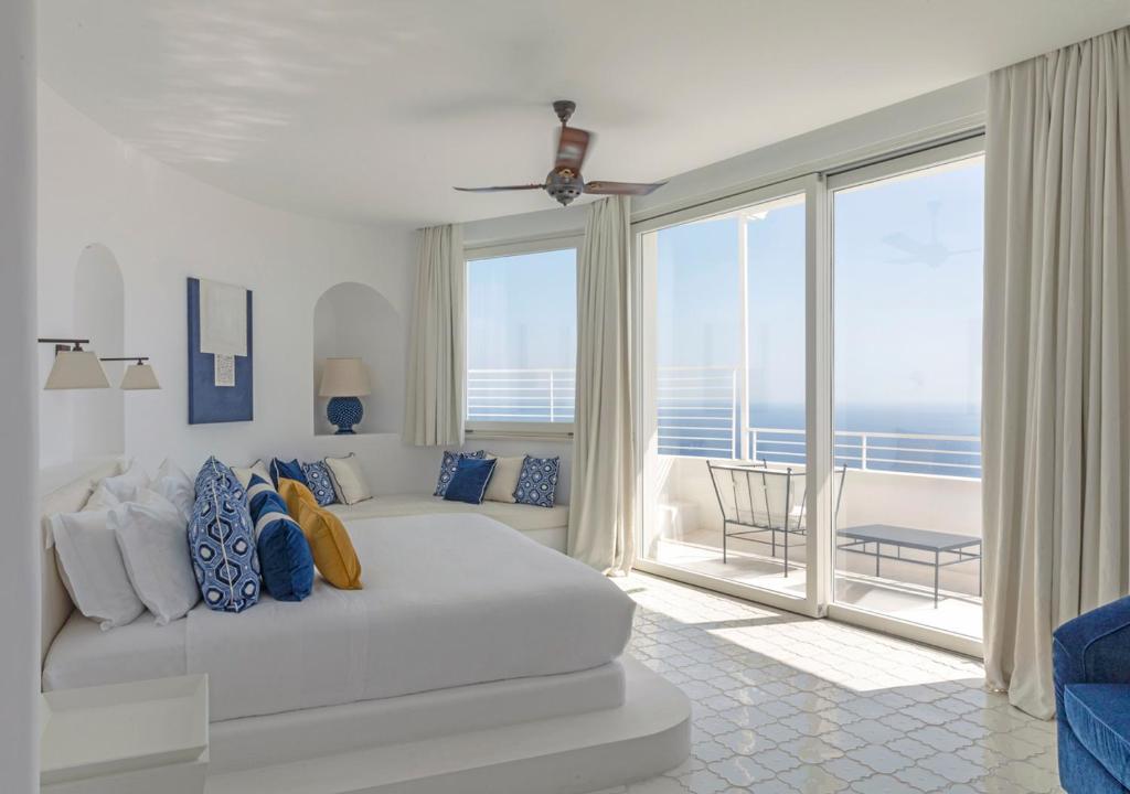 une chambre avec un lit blanc et une grande fenêtre dans l'établissement Furore Grand Hotel, à Furore 72 autres photos