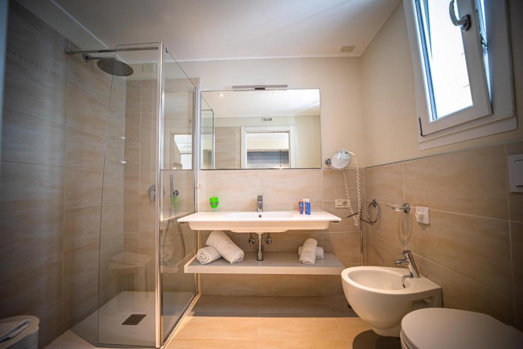 une salle de bain avec un lavabo, une douche et des toilettes dans l'établissement Hotel San Michele, à Bibione