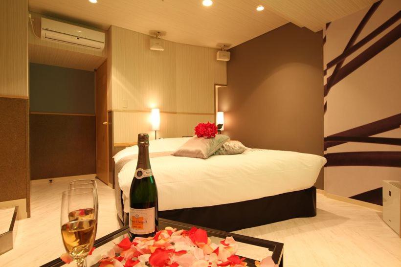 - une chambre avec un lit, une bouteille de vin et un plateau de fleurs dans l'établissement ホテルミュゼ愛子Hotel MUSEE Ayashi, à Sendai