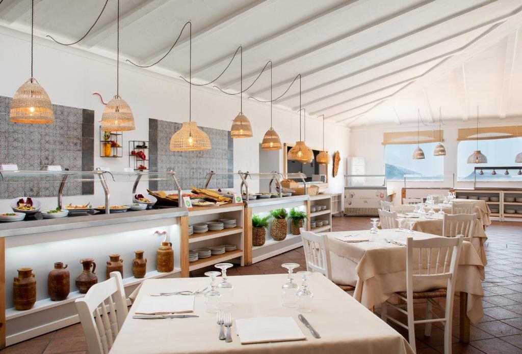 un restaurant avec des tables et des chaises et une cuisine dans l'établissement VOI Colonna Village, à Golfo Aranci