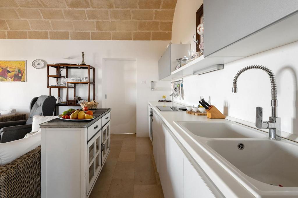 une cuisine blanche avec un évier et un comptoir dans l'établissement Villa Ella, à Castrignano del Capo