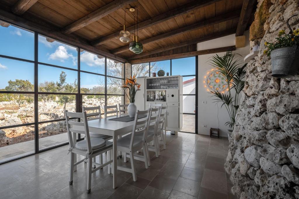 une salle à manger avec une table, des chaises et des fenêtres dans l'établissement Villa Ella, à Castrignano del Capo