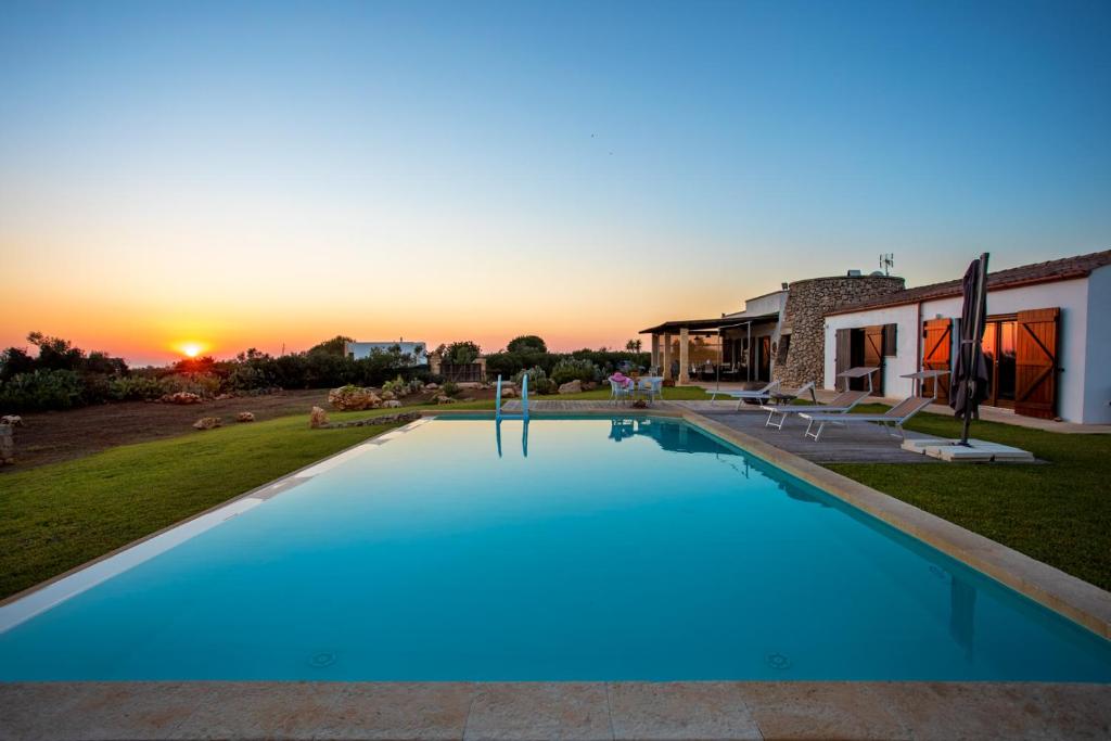 une grande piscine avec un coucher de soleil en arrière-plan dans l'établissement Villa Ella, à Castrignano del Capo