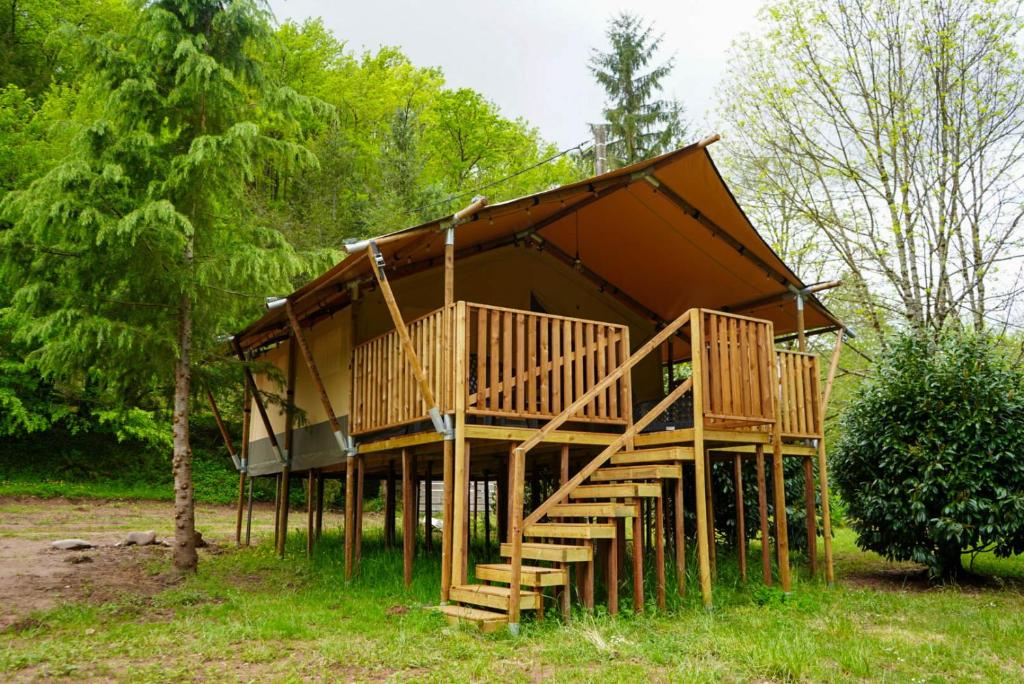 une grande maison en bois avec des escaliers dans une forêt dans l'établissement Camping Pittoresque, à Saint-Parthem 16 autres photos