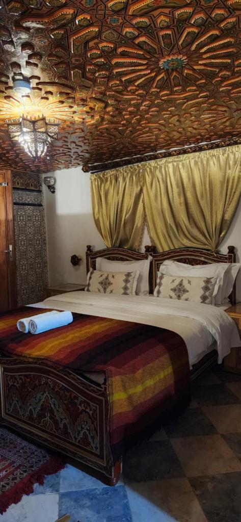 une chambre avec un grand lit avec un plafond en bois dans l'établissement Riad Royal, à Meknès