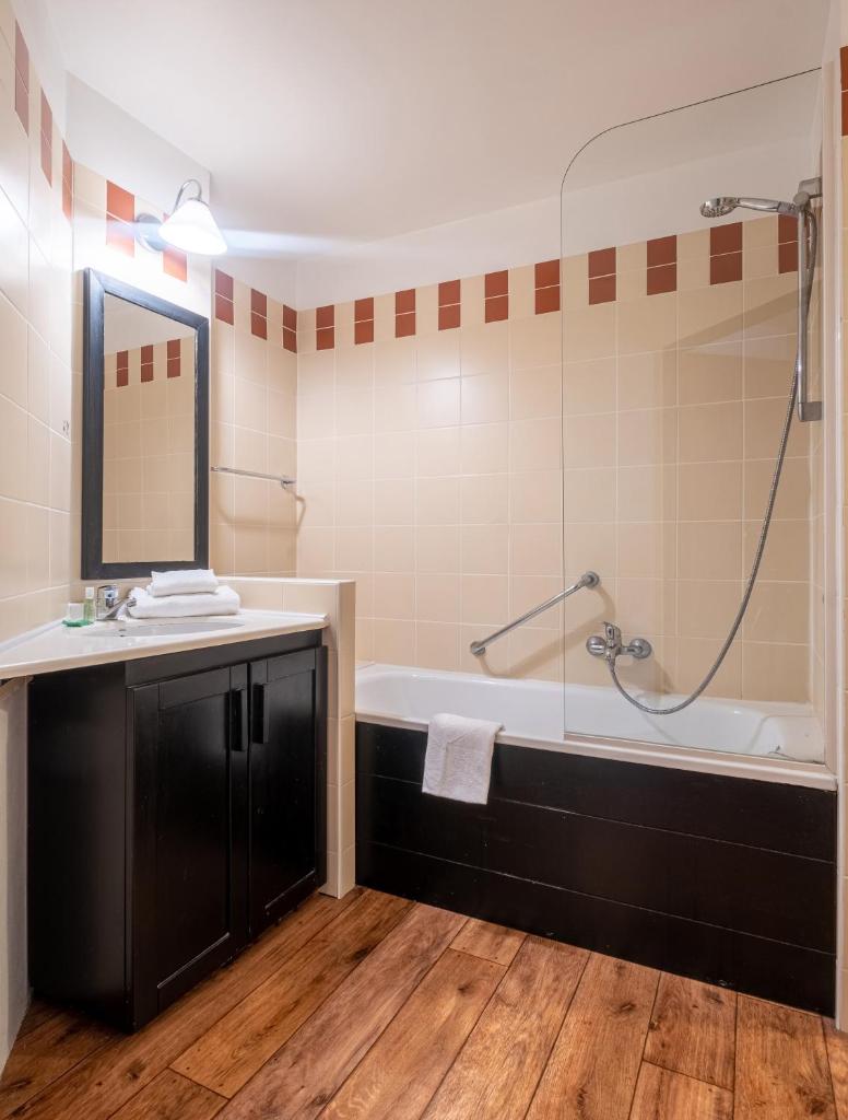 une salle de bain avec une baignoire, un lavabo et un miroir dans l'établissement Résidence Pierre & Vacances Le Tikal, à Val Thorens