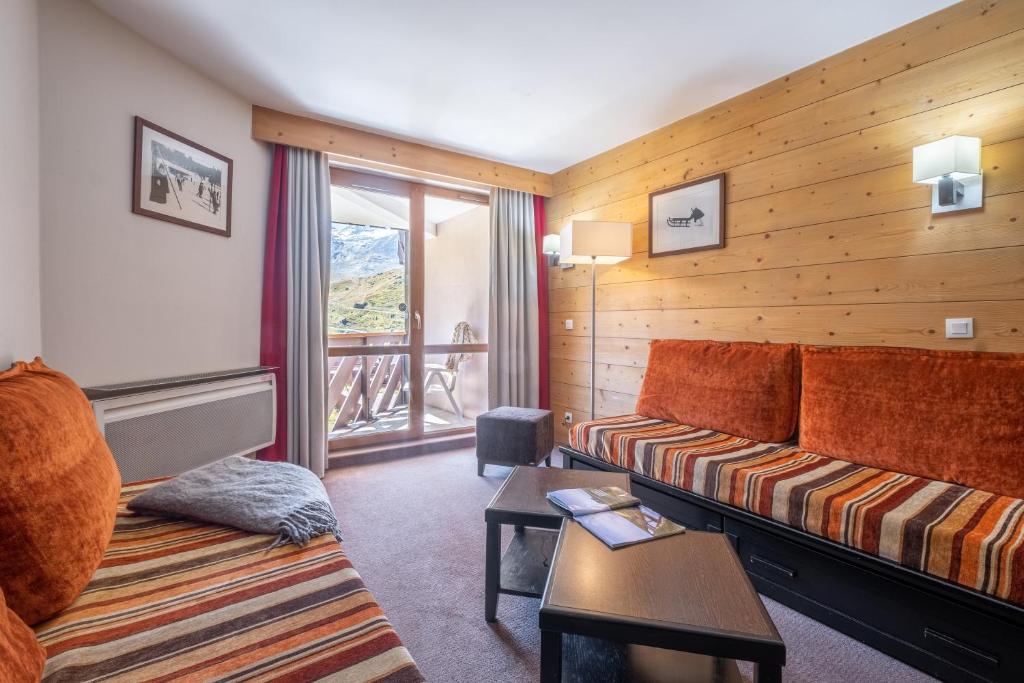 un salon avec un canapé et une fenêtre dans l'établissement Résidence Pierre & Vacances Le Tikal, à Val Thorens