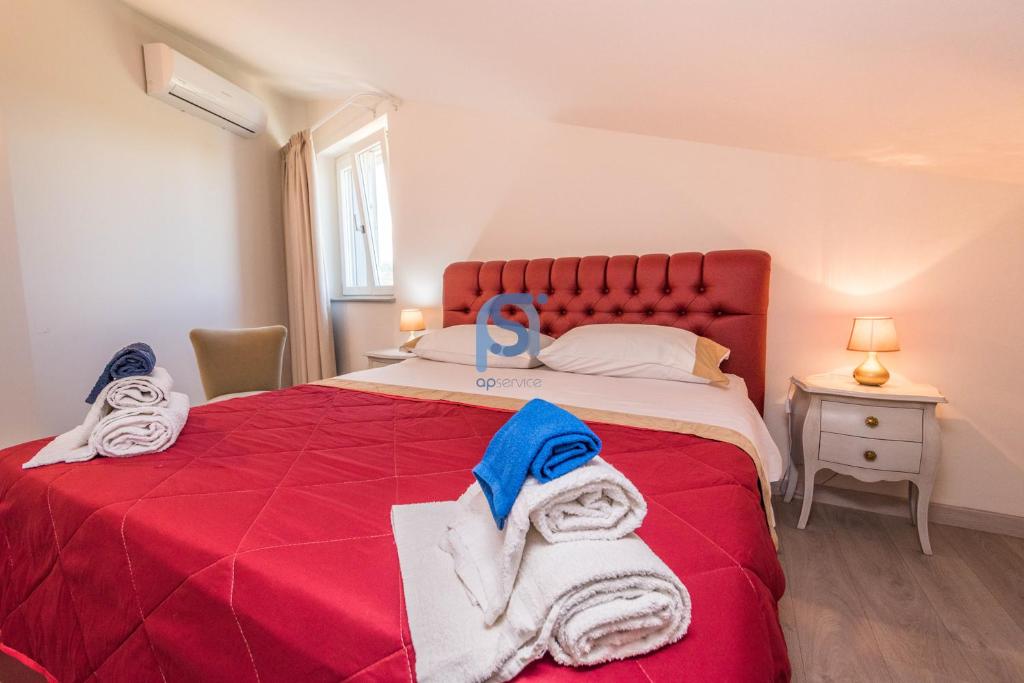 une chambre avec un lit rouge avec des serviettes dessus dans l'établissement Villa Azzurra con piscina privata, à Lascari