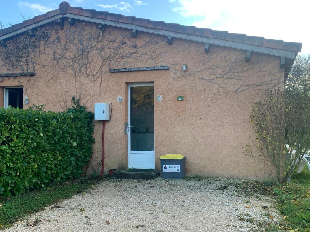 une maison en briques avec une porte et une poubelle dans l'établissement Camping Familial paisible avec piscine, mobil home , chalet, Studio & emplacement nue, à Casties-Labrande