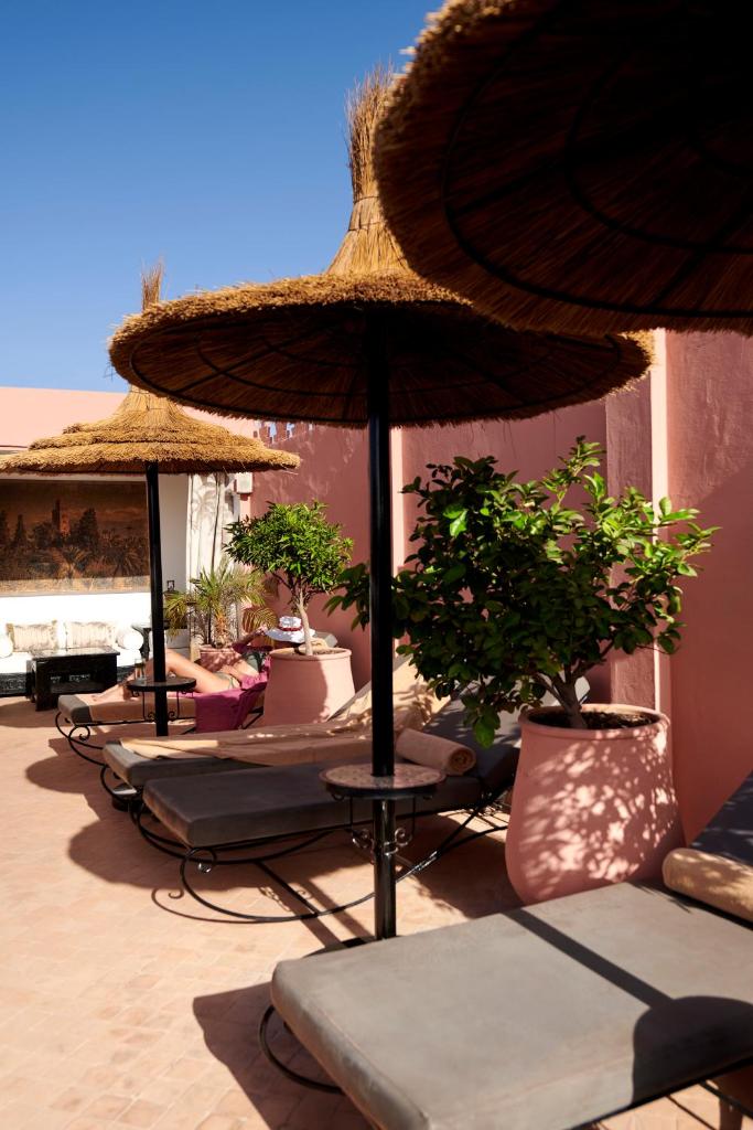 une rangée de parasols et de chaises longues avec des plantes dans l'établissement Riad Dar Amanza en exclusivité avec 4 chambres au coeur de la médina, à Marrakech