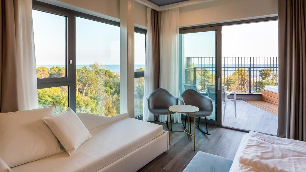- un salon avec un canapé et de grandes fenêtres dans l'établissement Mediterranee Family Hotel & Spa, à Bibione