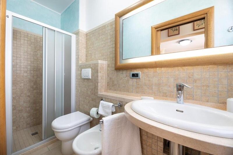 une salle de bain avec un lavabo, des toilettes et un miroir dans l'établissement Villa Eleonora con piscina Fronte Mare, à Capilungo