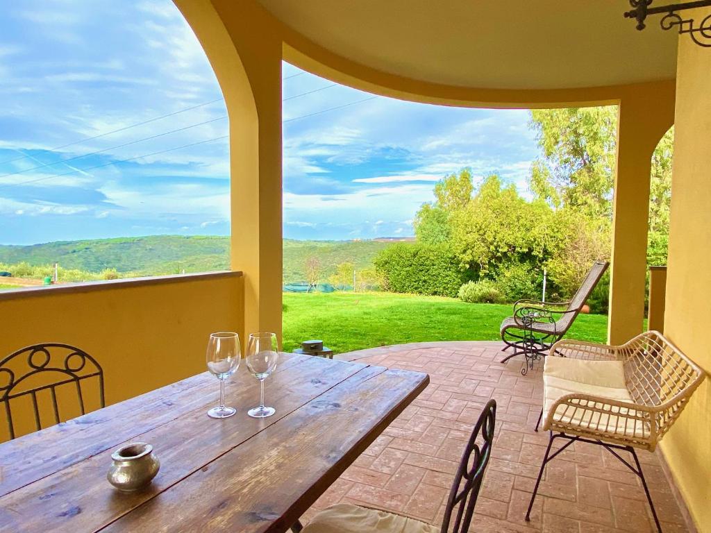 - une table en bois avec 2 verres à vin sur la terrasse dans l'établissement Villa Toscagialla, à San Vincenzo
