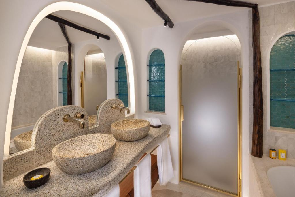 deux lavabos dans une salle de bain avec deux miroirs dans l'établissement Hotel Cala di Volpe, a Luxury Collection Hotel, Costa Smeralda, à Porto Cervo