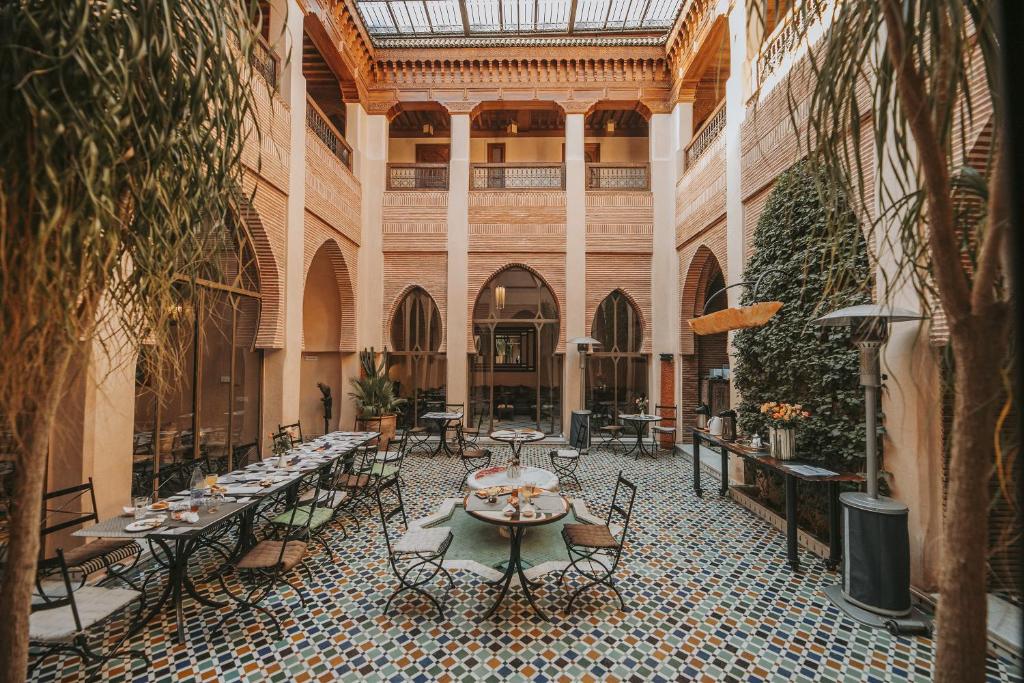 une cour avec des tables et des chaises dans un bâtiment dans l'établissement Riad Le Perroquet Bleu Suites & Spa, à Marrakech