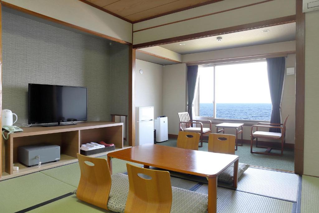 un salon avec une table et une télévision dans l'établissement Ooedo Onsen Monogatari Beppu Seifu, à Beppu