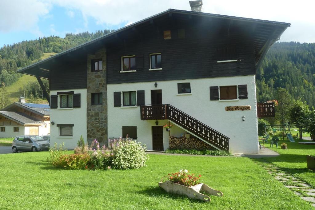 une grande maison blanche avec un toit noir dans l'établissement Chalet "les Arcosses", à La Giettaz