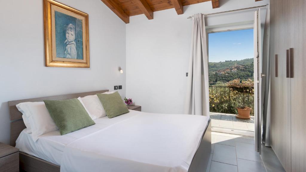 une chambre avec un lit blanc et une grande fenêtre dans l'établissement VILLA VITTORIO 6&2 Emma Villas, à Imperia
