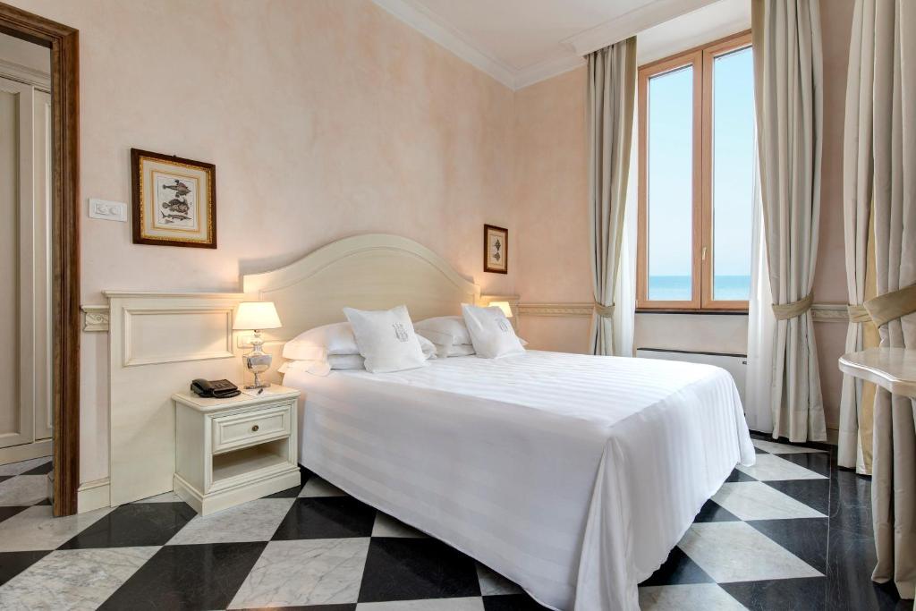 une chambre avec un grand lit blanc et une fenêtre dans l'établissement Hotel Cenobio Dei Dogi, à Camogli