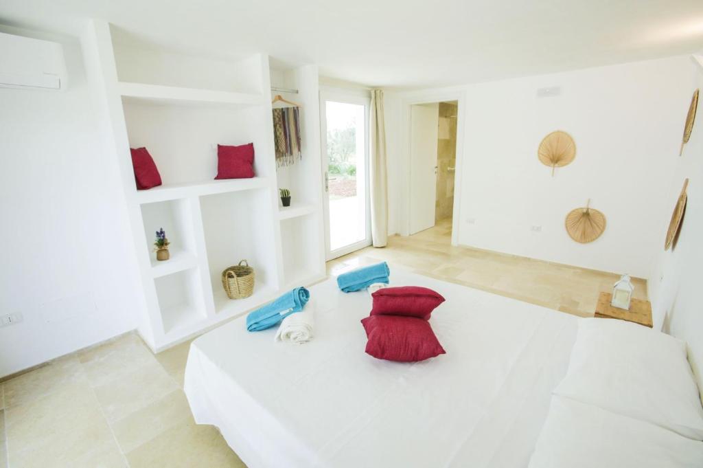 une chambre blanche avec un lit et une chaise rouge dans l'établissement Villa Gabriella by Villa Plus, à Carovigno