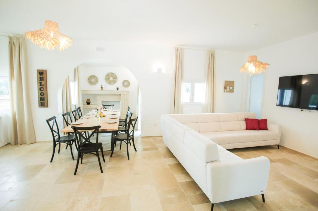 un salon avec un canapé blanc, une table et des chaises dans l'établissement Villa Gabriella by Villa Plus, à Carovigno