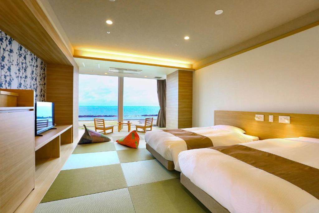 une chambre d'hôtel avec trois lits et une télévision dans l'établissement Ooedo Onsen Monogatari Premium Shiomiso, à Murakami