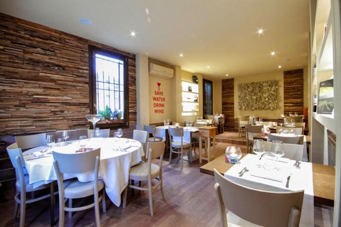 un restaurant avec des tables et des chaises blanches et un mur en briques dans l'établissement Casale IL SAMBUCO sui colli bolognesi, à San Lazzaro di Savena