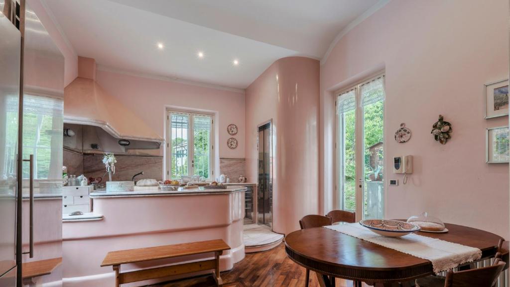 une cuisine et une salle à manger avec des murs roses et une table dans l'établissement VILLA LIBERTY ALBISOLA 6&2, Emma Villas, à Albisola Superiore