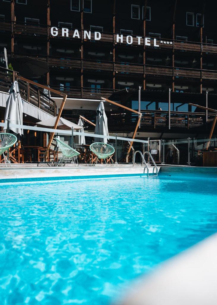 - une piscine avec des tables et des chaises dans un stade dans l'établissement Grand Hôtel & Spa NUXE Serre Chevalier, à Saint-Chaffrey