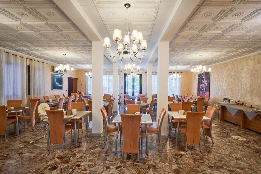 une salle à manger avec tables et chaises et un lustre dans l'établissement Hotel Villa Del Mar, à Bibione
