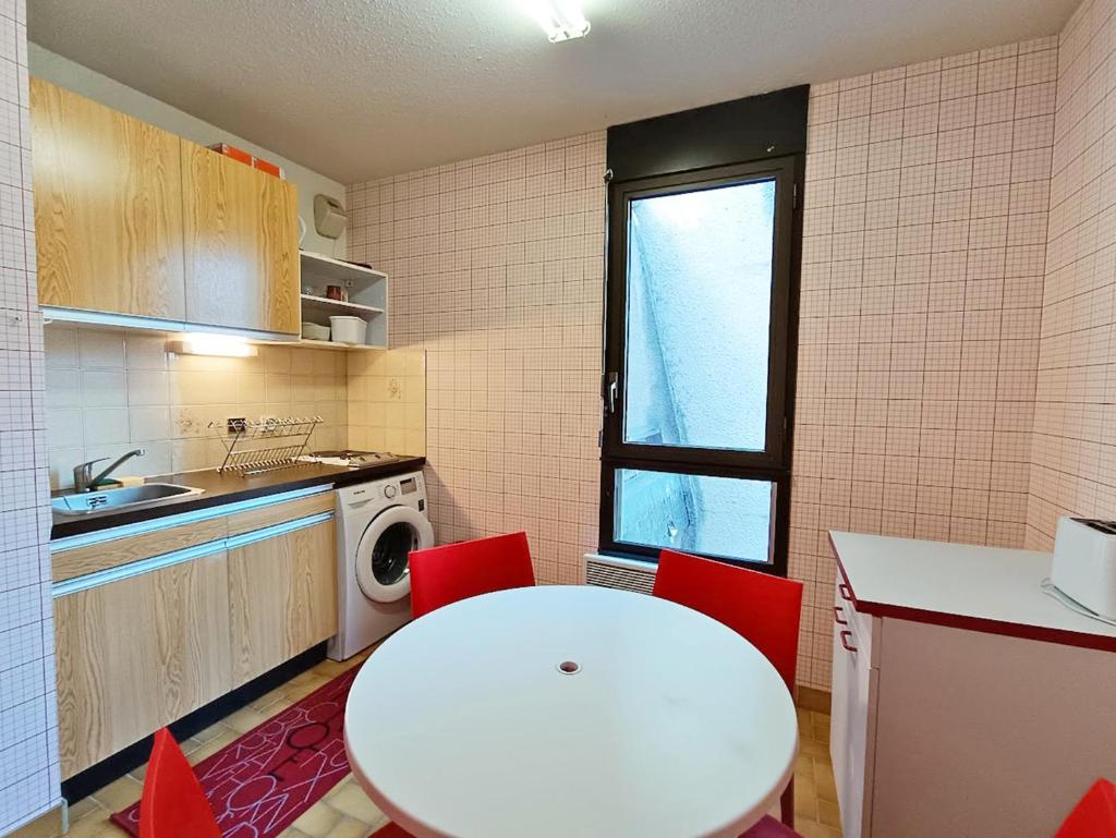 une petite cuisine avec une table blanche et des chaises rouges dans l'établissement Frolise, T2, centre, wifi, parking couvert gratuit, 4 personnes, à Luchon 12 autres photos