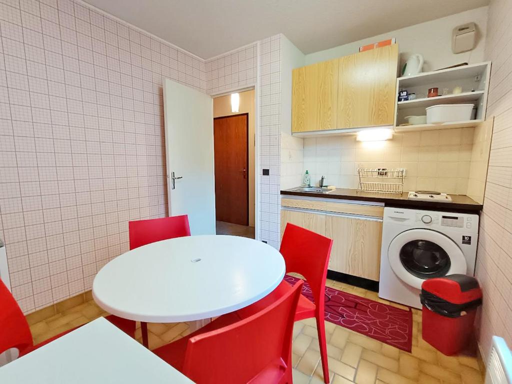 une petite cuisine avec une table blanche et des chaises rouges dans l'établissement Frolise, T2, centre, wifi, parking couvert gratuit, 4 personnes, à Luchon