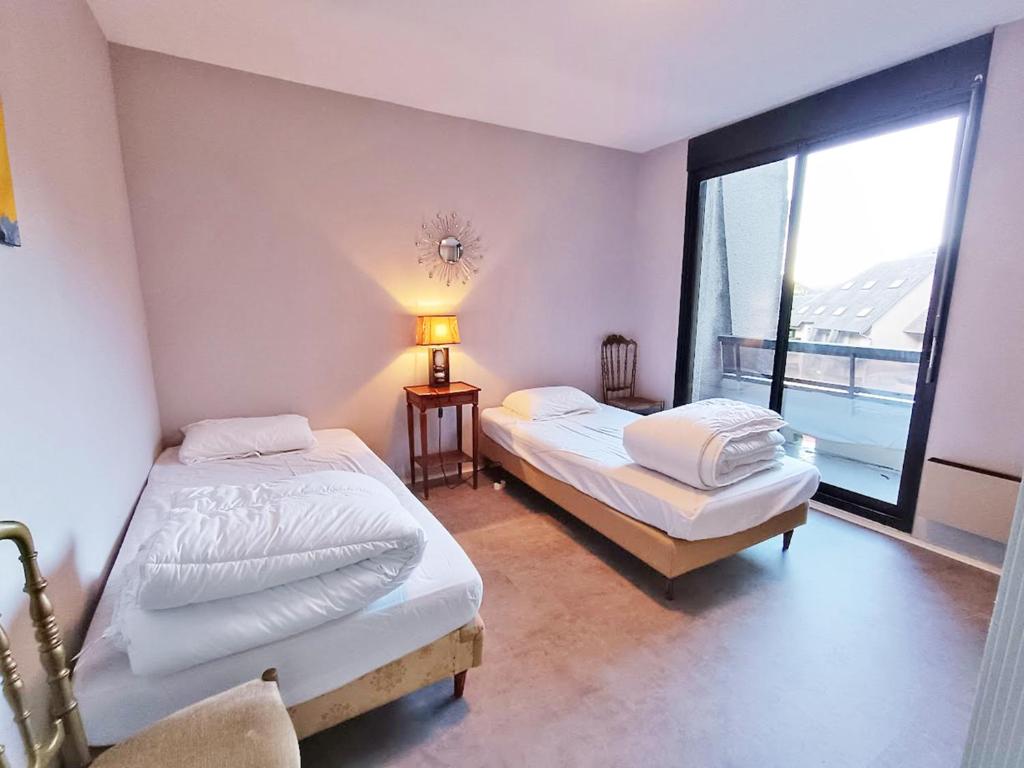 deux lits dans une chambre avec une grande fenêtre dans l'établissement Frolise, T2, centre, wifi, parking couvert gratuit, 4 personnes, à Luchon