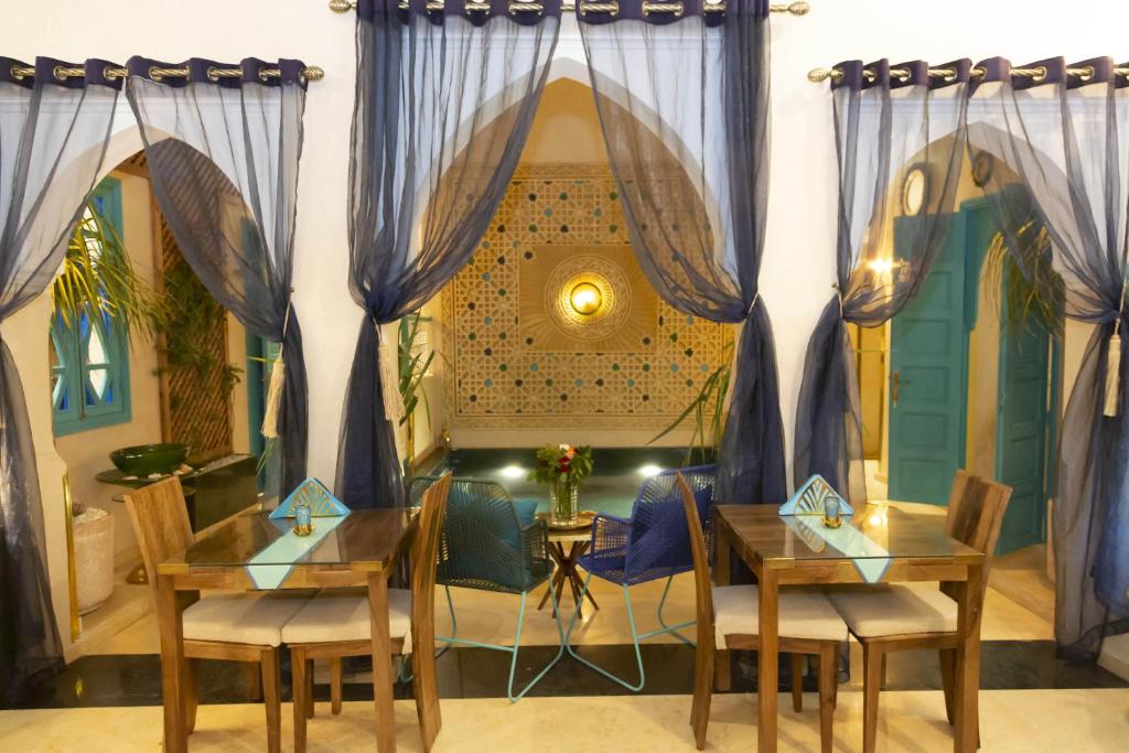 Cette chambre comprend deux tables, des chaises et des rideaux. dans l'établissement Riad La Rose Orientale Marrakech, à Marrakech