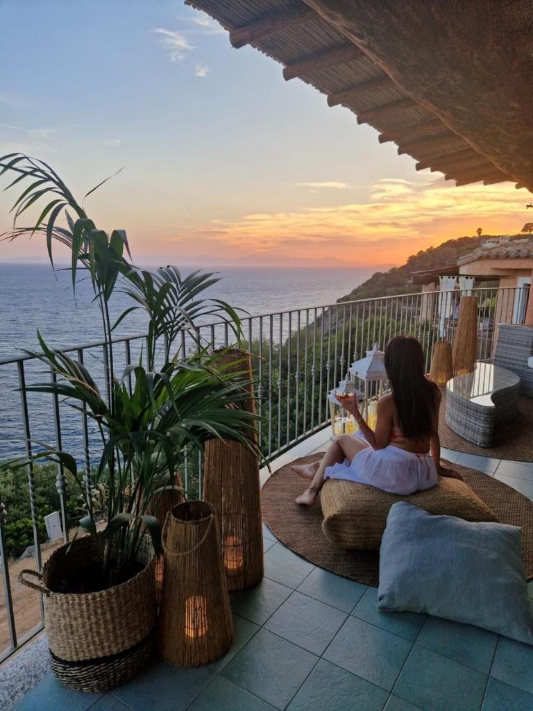 une femme assise sur un balcon pour lire un livre dans l'établissement Villa Gemma Torre delle Stelle Coast with infinity pool panoramic terraces and garden, à Torre delle Stelle