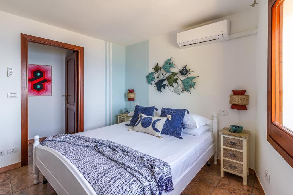 une chambre avec un lit blanc avec des oreillers bleus dans l'établissement Villa Gemma Torre delle Stelle Coast with infinity pool panoramic terraces and garden, à Torre delle Stelle 50 autres photos