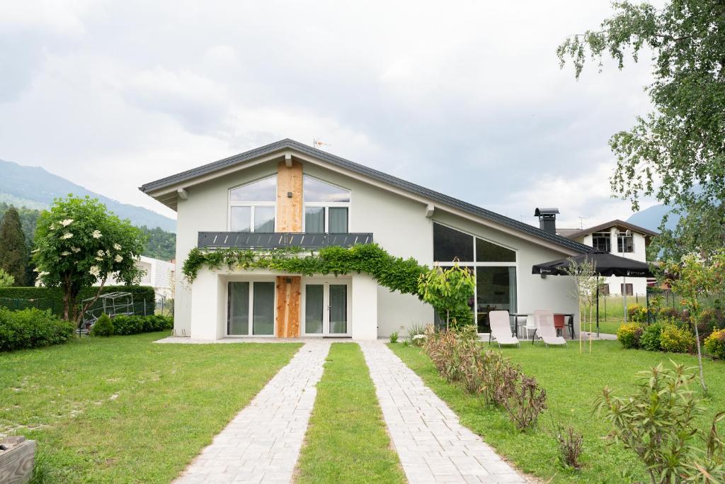 une maison blanche avec une cour d'herbe dans l'établissement Caldonazzo Dog Sport & Wellness, à Caldonazzo